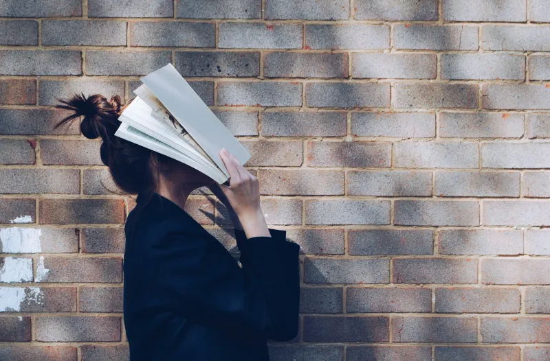 Jeune fille la tête dans un livre, dépassée par Parcoursup